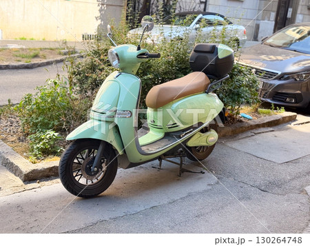Mint green retro scooter with beige seat parked on city street near sidewalk. Urban mobility, eco transport, and stylish modern lifestyle Mint green retro scooter with beige seat parked on city street near sidewalk. Urban mobility, eco transport, and stylish modern lifestyle 130264748