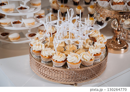 Elegant dessert table with assorted mini cakes and creamy cupcakes at festive event Elegant dessert table with assorted mini cakes and creamy cupcakes at festive event 130264770