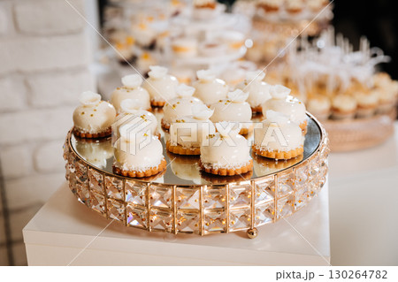 Elegant vanilla cream profiteroles on a golden stand at festive dessert table display 130264782