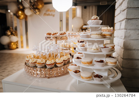 Elegant dessert table with white mousse cubes on cookies in luxury golden trays 130264784