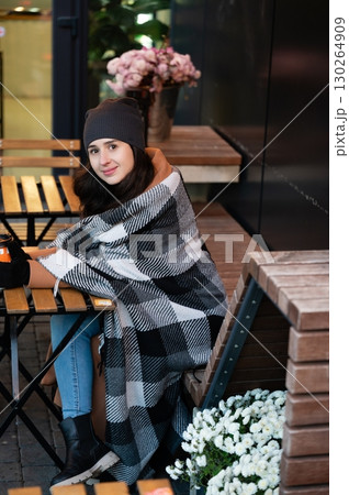 Cozy winter afternoon with a warm blanket and a cup of tea in a stylish cafe adorned with beautiful flowers and wooden furnishings Cozy winter afternoon with a warm blanket and a cup of tea in a stylish cafe adorned with beautiful flowers and wooden furnishings 130264909