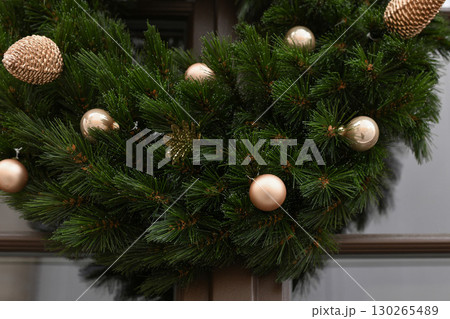 Christmas wreath with branches and golden balls on a glass door Christmas wreath with branches and golden balls on a glass door 130265489