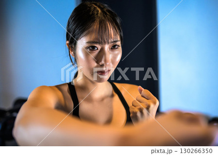 ジムでボクササイズ運動するかっこいい女性　右の拳で殴る　パンチ 130266350