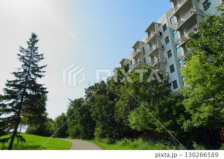 Modern apartment building with green trees and walkway 130266589