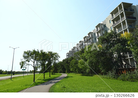 Modern apartment building with green trees and walkway 130266626