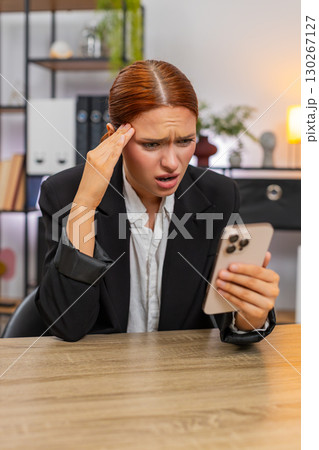 Young businesswoman despairs over big failure online game loss reading bad news sadly on smartphone 130267127