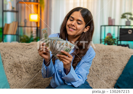 Indian woman counting cash dollars with satisfied smile, feeling financial success and wealth 130267215