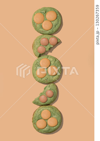 Pistachio cookies with creamy filling arranged vertically on a peach background, showcasing vibrant colors and textures, ideal for bakery concept and menu design with copy space 130267359