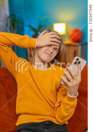 Teenager boy checking smartphone, looks sad, receives bad news negative test results sitting on sofa 130267446