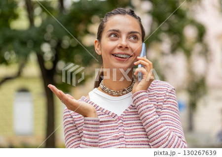 Happy woman in pleasant conversation on smartphone enjoying talking chat with friends on city street Happy woman in pleasant conversation on smartphone enjoying talking chat with friends on city street 130267639
