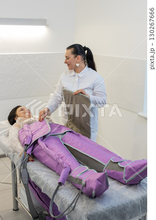 Cosmetology therapist doctor making pressotherapy procedure treatment for woman in a beauty salon Cosmetology therapist doctor making pressotherapy procedure treatment for woman in a beauty salon 130267666