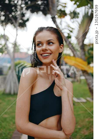 Woman in a stylish black one piece bathing suit posing gracefully for a photo shoot in the park on a sunny day 130267699