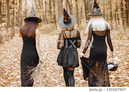 Three girls witches in forest on Halloween. Girls wearing black dresses and cone hats. Witches dance to make a magic potion. 130267907