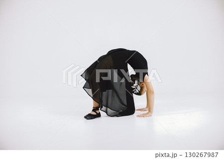 Little ballerina on white background. Brunette girl wearing black ballet suit. Girl doing gymnastic excercises. Little ballerina on white background. Brunette girl wearing black ballet suit. Girl doing gymnastic excercises. 130267987
