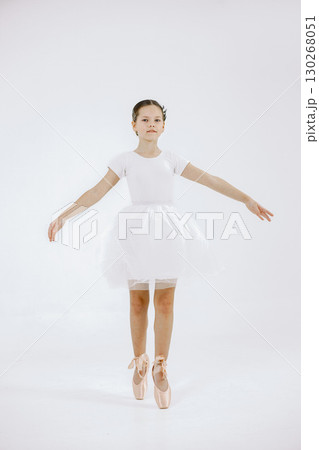 Little ballerina on white background. Brunette girl wearing white ballet suit. Girl standing on her toes. Little ballerina on white background. Brunette girl wearing white ballet suit. Girl standing on her toes. 130268051