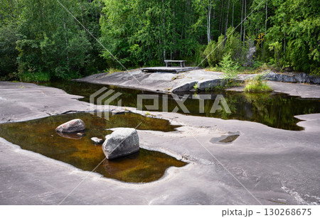 Tranquil forest scene with rock formations and calm water reflections, landscape with stone and trees in Zalavruga, Karelia. Tranquil forest scene with rock formations and calm water reflections, landscape with stone and trees in Zalavruga, Karelia. 130268675