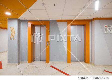 The modern elevator lobby features vibrant orange accents, making it bright and inviting The modern elevator lobby features vibrant orange accents, making it bright and inviting 130268780