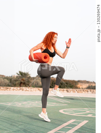 Fit woman in activewear exercising outdoors while 130269474