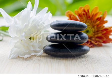 Green leaves and white bloom paired with zen stones refreshing calm with customizable space for text Green leaves and white bloom paired with zen stones refreshing calm with customizable space for text 130269932