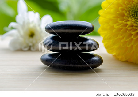Elegant zen stones with vibrant yellow flower on wooden background with customizable space for text 130269935