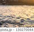 Drops of water fallling to the ocean at sunset closeup. 130270044