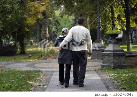 An elderly couple, man and woman walk in the autumn park. An elderly couple, man and woman walk in the autumn park. 130270045