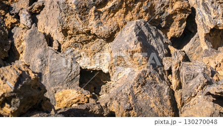 Lava formations, stones, black basalt in the rocks closeup on a volcano terrain. Lava formations, stones, black basalt in the rocks closeup on a volcano terrain. 130270048