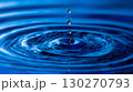 A close-up shot shows water droplets falling into a body of water, creating concentric ripples on the surface. Water droplet impact showing ripple effect and reflection in the water surface. 130270793