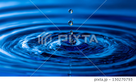 A close-up shot shows water droplets falling into a body of water, creating concentric ripples on the surface. Water droplet impact showing ripple effect and reflection in the water surface. A close-up shot shows water droplets falling into a body of water, creating concentric ripples on the surface. Water droplet impact showing ripple effect and reflection in the water surface. 130270793