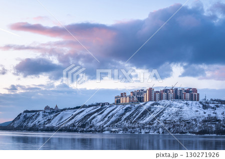 Residential neighborhood on the banks of the Yenisei River on a frosty winter evening, Krasnoyarsk, Russia. A Beautiful Winter Landscape featuring Snowy Hills harmoniously alongside Modern Buildings 130271926