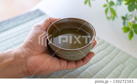 一杯の飲み物を手に取る日本人男性の手 130272383