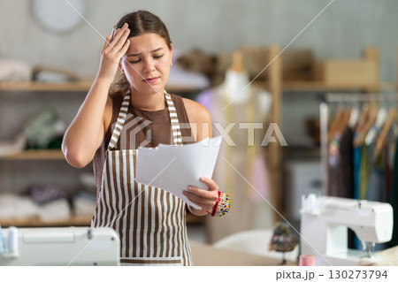 woman dressmaker looks at her documents in frustration 130273794