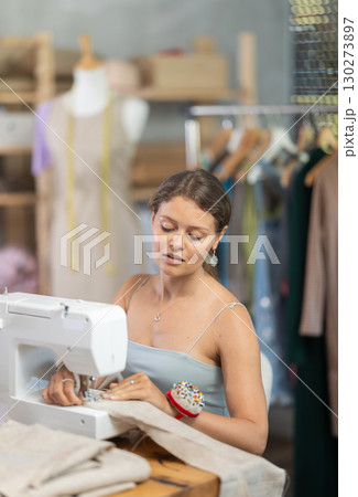 Female tailor using sewing machine to make garment in studio Female tailor using sewing machine to make garment in studio 130273897