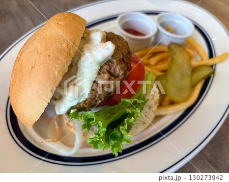 お皿に乗ったハンバーガーとフライドポテトとピクルス 130273942