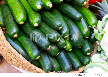 Bunch of ripe green zucchinis in wicker basket 130273990