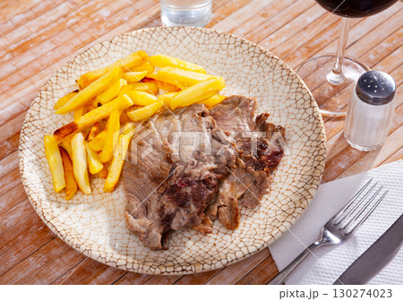 Pork chop with French fries on a plate. Pork chop with French fries on a plate. 130274023