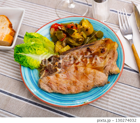 Juicy roast pork on a plate with stewed vegetables 130274032