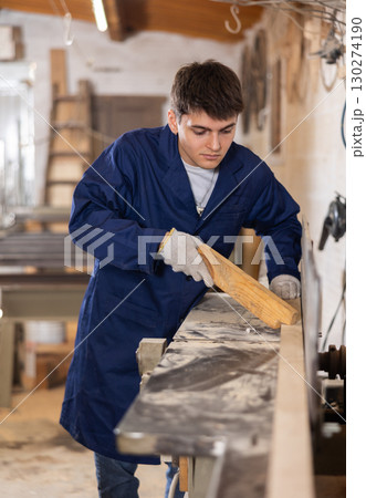 Young guy working with wooden board on workbench 130274190