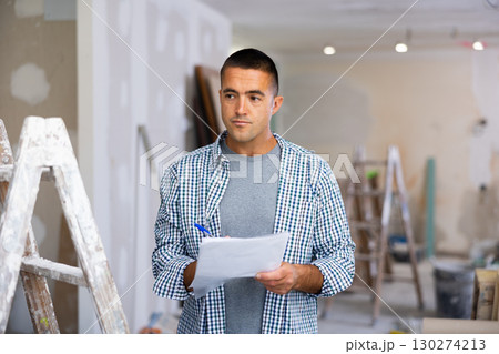 Man designer checking documents during repair works 130274213