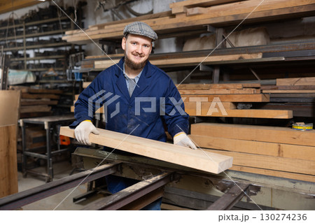 Young man putting wooden board on cutting machine 130274236