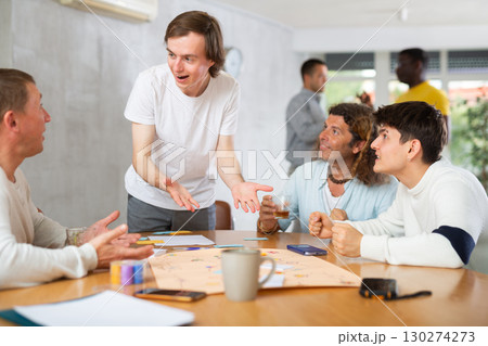 Cheerful guy playing board game with male friends 130274273