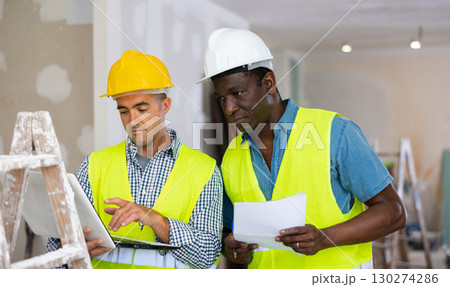 Man builder examining project documentation in apartment 130274286