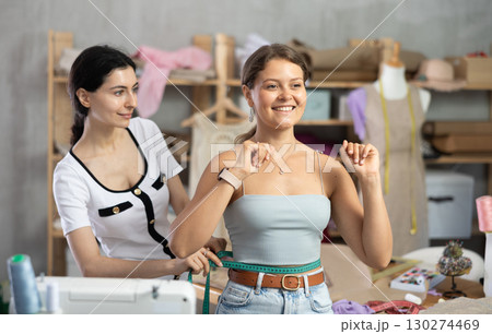 dressmaker takes measurements from the client 130274469