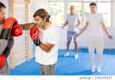Men in boxing gloves punch deliver blow each other during training sparring session. Men in boxing gloves punch deliver blow each other during training sparring session. 130274527