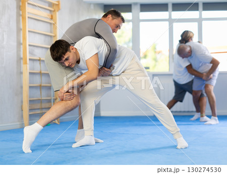 Guy learns to do power throws with a coach during judo or sambo classes Guy learns to do power throws with a coach during judo or sambo classes 130274530