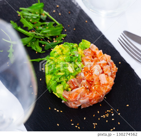 Salmon tartare with avocado garnished with greens on slate board 130274562