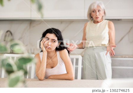 Elderly woman quarreling with young woman in kitchen Elderly woman quarreling with young woman in kitchen 130274625