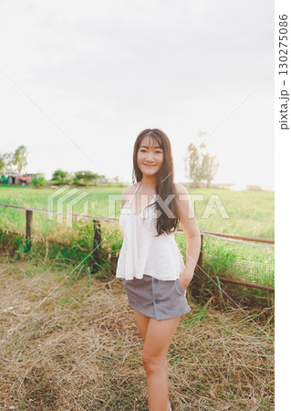 Beautiful Asian woman wearing sexy dress, smiling happily on vacation. 130275086