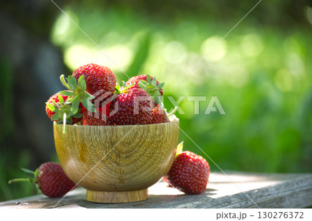 Fresh Strawberries in Wooden Bowl on Rustic Table Outdoors 130276372