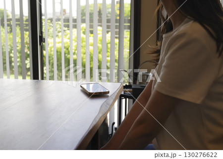 薄暗い室内で椅子にすわっている女性 薄暗い室内で椅子にすわっている女性 130276622